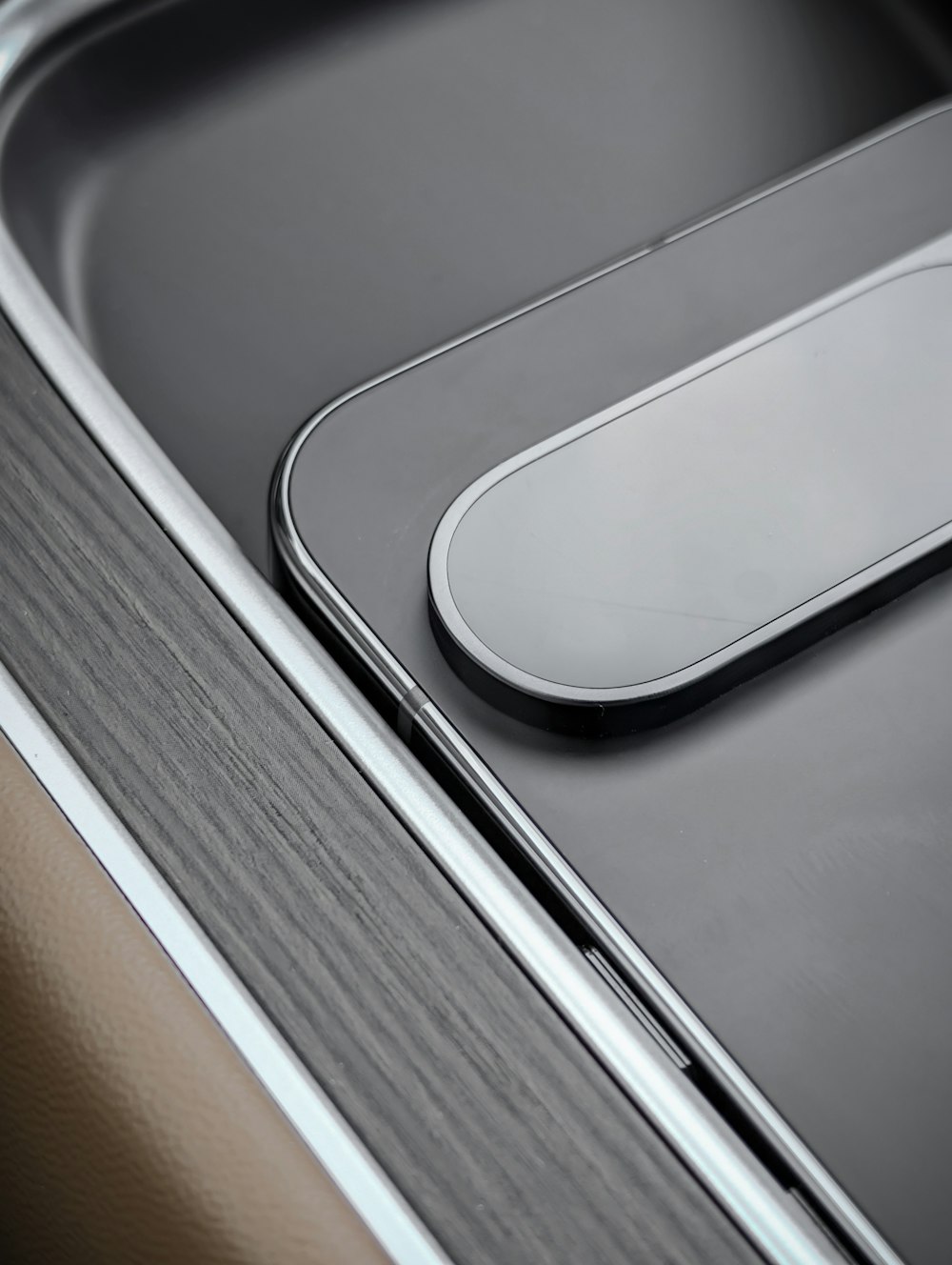 Detail of a modern EV interior console with wood trim and satin metal accents